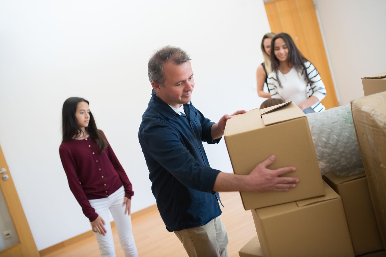 Family moving into their new home, unpacking boxes together indoors.